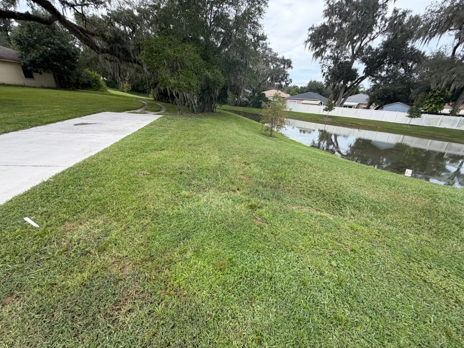 Mowed common area beside a walking path and pond