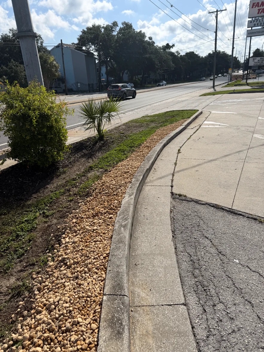 Clean river rock edging along a commercial entrance curb